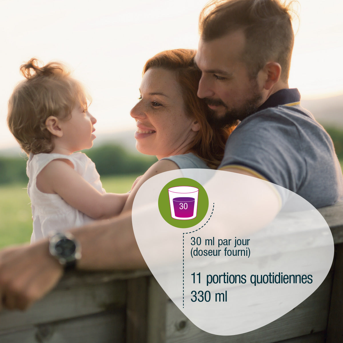 Eine lächelnde Familie sitzt im Freien an einem Holzzaun. Ein Overlay zeigt ein Messbecher-Symbol mit französischem Text: Eisen Vital Complex (Bio) FR von gse.organic.supplements-30 ml täglich für das Immunsystem.