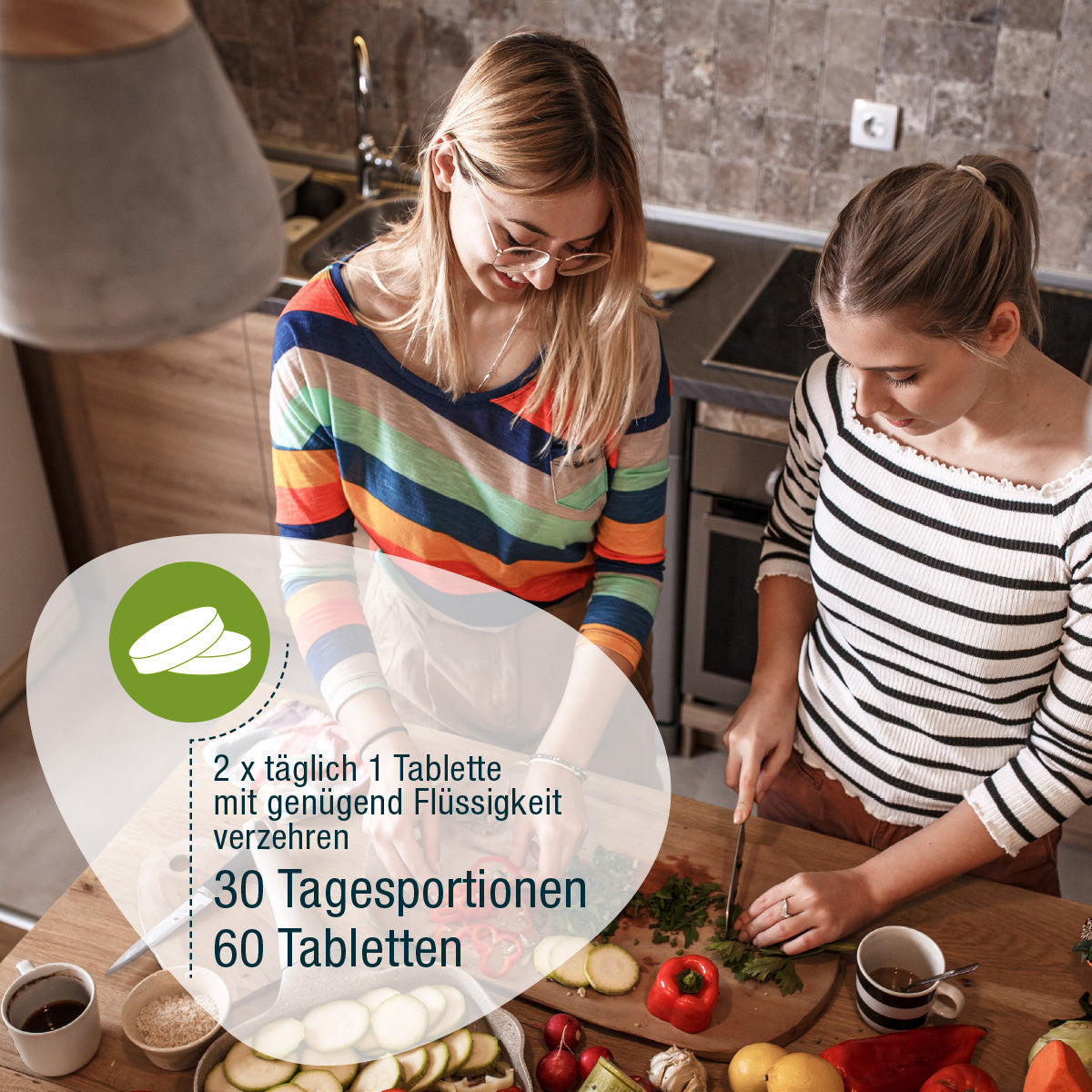 Zwei Frauen in einer Küche bereiten frisches Gemüse zu, wobei sie pflanzliche Nährstoffe verwenden. Sie verwenden gse.organic.supplements VeganPlus (Bio): 2 x täglich 1 Tablette, 30 Tagesportionen, 60 Tabletten. Der eine schneidet, der andere schaut zu.