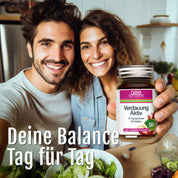 Ein lächelnder Mann und eine lächelnde Frau machen ein Selfie in einer Küche, während die Frau Verdauung Aktiv (Bio), ein Verdauungsergänzungsmittel, in der Hand hält. Frisches Gemüse liegt auf der Theke. Text: Deine Balance - Tag für Tag.