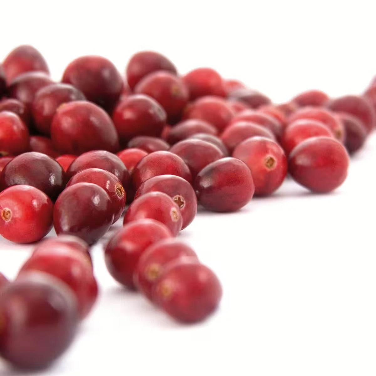 Eine Nahaufnahme von Urovit®-Cranberry Pulver von gse.organic.supplements, verstreut auf einer weißen Oberfläche mit glatter, glänzender roter Schale, die an leuchtende Cranberries erinnert und reich an Proanthocyanidinen ist.